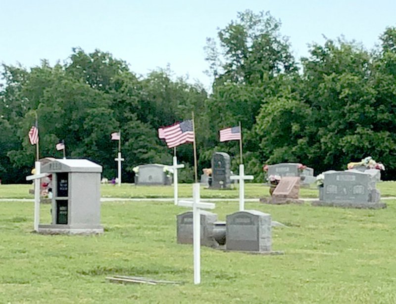 Westside Eagle Observer/SUBMITTED PHOTO Local veterans groups join the Decatur Veterans Committee May 19 to place wooden crosses on graves of military veterans buried at Decatur Cemetery in Decatur. The flags were place at the crosses to prepare for the Memorial Day weekend.