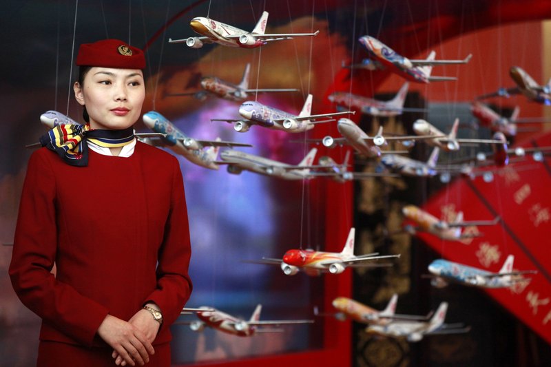 FILE - In this June 12, 2012, file photo, an Air China flight attendant stands near model planes at the International Air Transport Association (IATA) 68th Annual General Meeting (AGM) and World Air Transport Summit in Beijing. (AP Photo/Ng Han Guan, File)