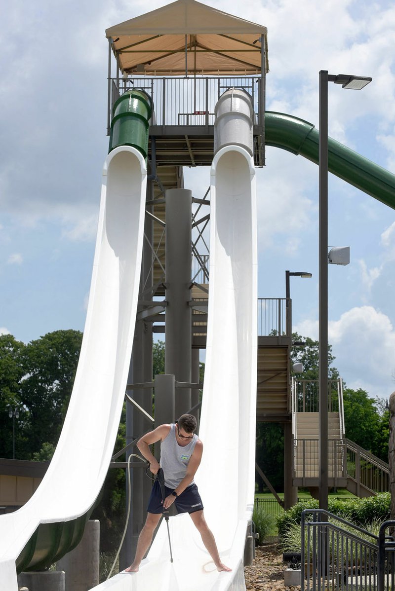 NWA Democrat-Gazette/FLIP PUTTHOFF Cory Beemer, a lifeguard at the Rogers Aquatics Center, cleans slides Tuesday to get the center ready to open. The center opens at 11 a.m. Saturday, said Leanne Jacobson, a supervisor at the center. Splash Passes good for 10 admissions are on sale at half price through Monday. Cost is $42.50 for Rogers residents or $49.50 for nonresidents. This is the sixth season for the center. More than 82,000 admissions were recorded at the center last season, Jacobson said.
