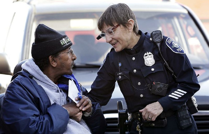 Seattle police officer Debra Pelich (right) wears a video camera on her eyeglasses as she talks with Alex Legesse before a small community gathering in Seattle. 