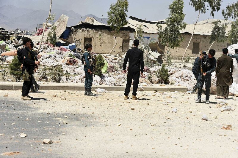 Afghan security personnel examine the site of Tuesday’s deadly explosion in Kandahar.  