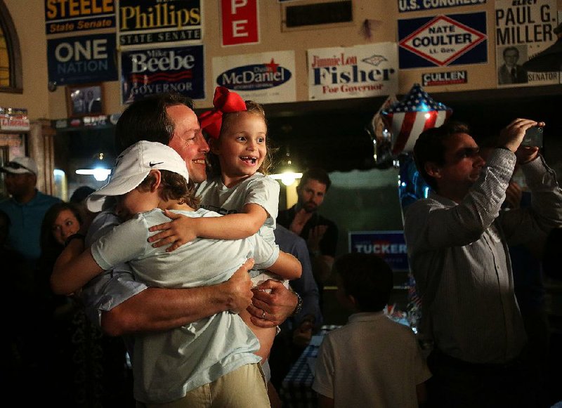 Clarke Tucker celebrates with his children Ellis (left) and Mari Frances after making his victory speech Tuesday night at Cotham’s in the City in Little Rock. 