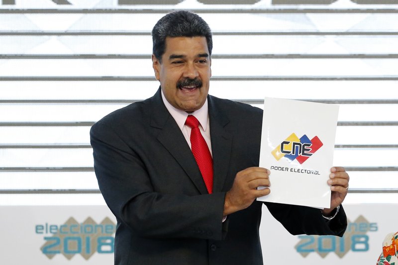Venezuela's President Nicolas Maduro holds up the National Electoral Council certificate declaring him the winner of the presidential election, during a ceremony at CNE headquarters in Caracas, Venezuela, Tuesday, May 22, 2018. (AP Photo/Ariana Cubillos)