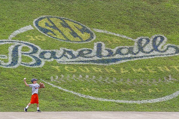 A young fan throws the ball under a tournament logo in the outfield during a rain delay in the seventh inning of a Southeastern Conference Tournament NCAA college baseball game between Georgia and Mississippi, Thursday, May 24, 2018, in Hoover, Ala. (AP Photo/Butch Dill)

