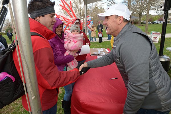 Arkansas football coach Chad Morris (right) shakes hands with David Carlton, a former player from Tulsa, Okla., his wife, Rebekah, and their 1-year-old daughter, Kinsley, Saturday, April 14, 2018, during the annual Hogfest, a fan appreciation day in The Gardens on the University of Arkansas campus in Fayetteville. 