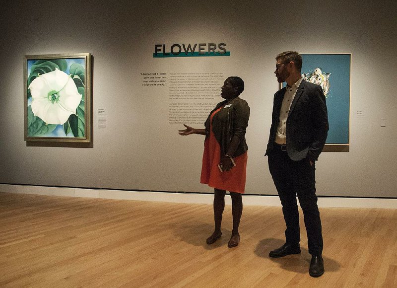 Lauren Haynes and Chad Alligood, co-curators of “The Beyond: Georgia O’Keeffe and Contemporary Art,” stand Thursday near O’Keeffe’s Jimson Weed/White Flower No. 1, part of the new exhibit at Crystal Bridges Museum of American Art in Bentonville. 