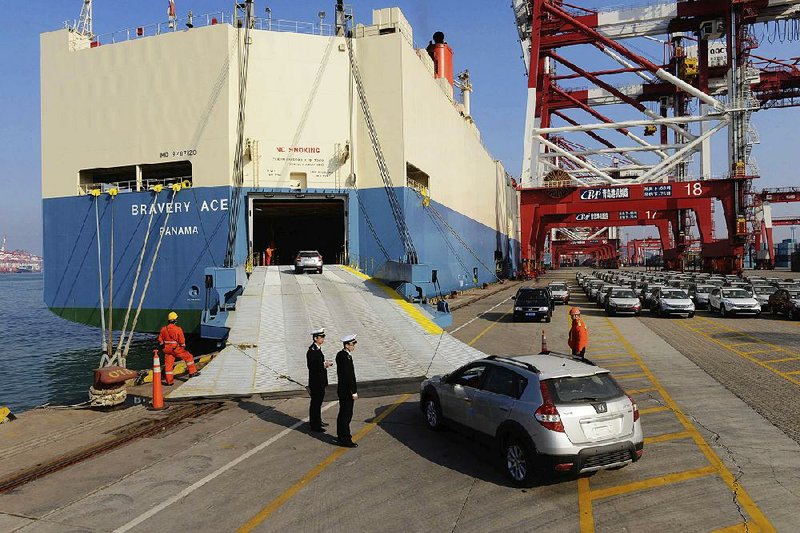 Chinese customs officials inspect cars being loaded for export at a port in Qingdao in eastern China in this 2015 file photo. China said Thursday it will “fi rmly defend” its rights and interests after U.S. President Donald Trump ordered an investigation into whether tariffs are needed on automobile imports on national security grounds. 