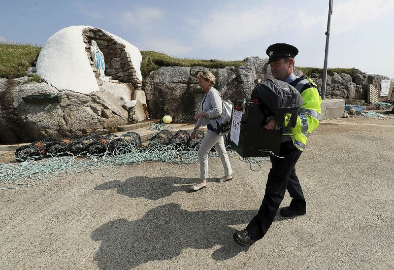 Police officer Pat McIlroy and local official Nancy Sharkey arrive Thursday will a ballot box for Gola Island residents to use to vote in today’s election on the Irish constitution. Residents of the island, off the coast of Donegal, Ireland, vote a day ahead of the rest of the nation. 