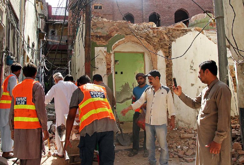 Volunteers in Sialkot, Pakistan, clean up Thursday at a mosque demolished by Sunni extremists. 