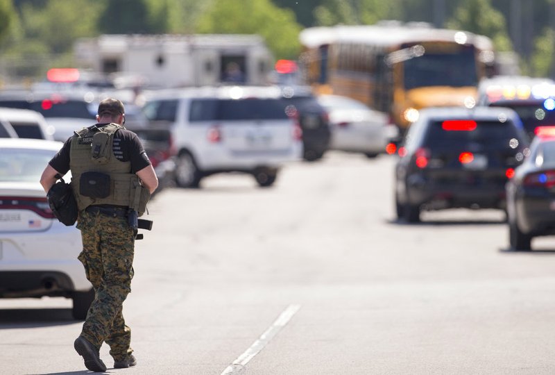 A law enforcement officer walks outside Noblesville West Middle School in Noblesville, Ind., after a shooting on Friday, May 25, 2018. A male student opened fire at the suburban Indianapolis school wounding another student and a teacher before being taken into custody, authorities said. (Robert Scheer/The Indianapolis Star via AP)