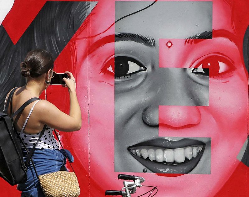 A woman in Dublin takes a photo Friday of a mural depicting Savita Halappanavar, a dentist who had sought and was denied an abortion before she died of a miscarriage in a case that was a catalyst for Friday’s vote on whether to repeal Ireland’s strict abortion ban. Results are expected today.  
