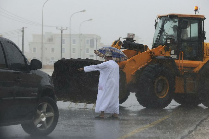 An Oman official directs a loader driver Friday to tear away a median to drain a flooded street in Salalah after Cyclone Mekunu’s heavy rains.  