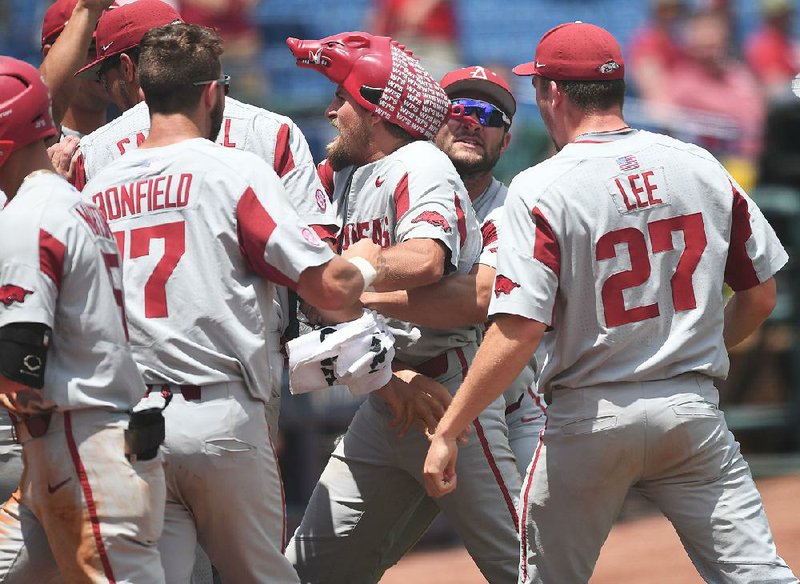 Arkansas’ Hunter Wilson (center) receives the Hog hat from his teammates after hitting a grand slam home run in the ninth inning Friday against Florida at the SEC Tournament in Hoover Ala. 