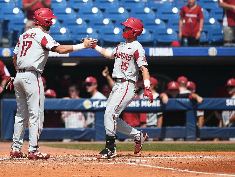 Arkansas freshman Casey Martin (right) is congratulated by Luke Bonfield after Martin’s home run in the second inning Friday against Florida. After Hunter Wilson’s grand slam in the ninth, the Razorbacks have 83 home runs for the season, tying last year’s total. The Hogs are nine home runs short of the school record of 92 in 2010. 