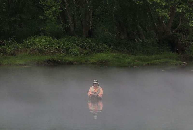 In this file photo fog rolls past a fly fisherman near the Barnett Access to the Little Red River in Heber Springs as he waits for a bite on his line. 