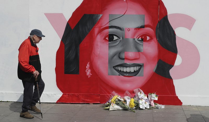 A man walks past a mural showing Savita Halappanavar, a 31-year-old Indian dentist who had sought and been denied an abortion before she died after a miscarriage in a Galway hospital, with the word YES over it, in Dublin, Ireland, on the day of a referendum on the 8th amendment of the constitution. The referendum on whether to repeal the country's strict anti-abortion law is being seen by anti-abortion activists as a last-ditch stand against what they view as a European norm of abortion-on-demand, while for pro-abortion rights advocates, it is a fundamental moment for declaring an Irish woman's right to choose. (Niall Carson/PA via AP)