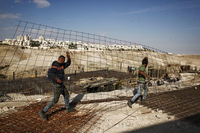 FILE - In this Jan. 22, 2017 file photo, workers carry material at a construction site in the West Bank settlement of Maaleh Adumim. Israeli Defense Minister Avigdor Lieberman said Thursday, May 24, 2018, that he will seek approval next week to fast-track construction of 2,500 new West Bank settlement homes this year and advance 1,400 more units that are currently in the planning stage. (AP Photo/Mahmoud Illean, File)