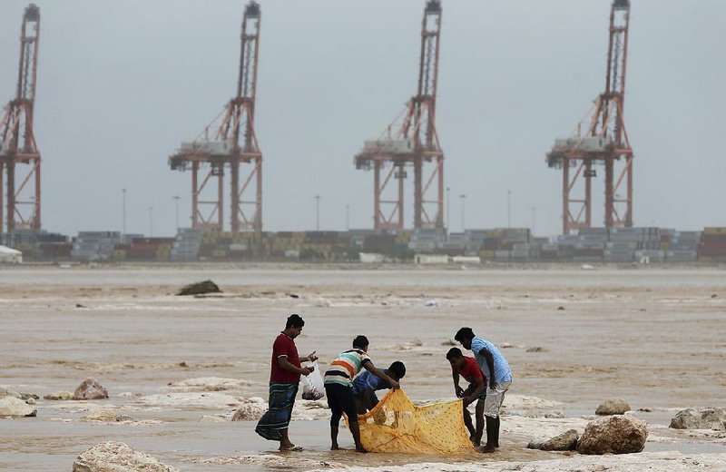 Asian workers fish Saturday in the floodwaters after Cyclone Merkunu struck in Salalah, Oman.  