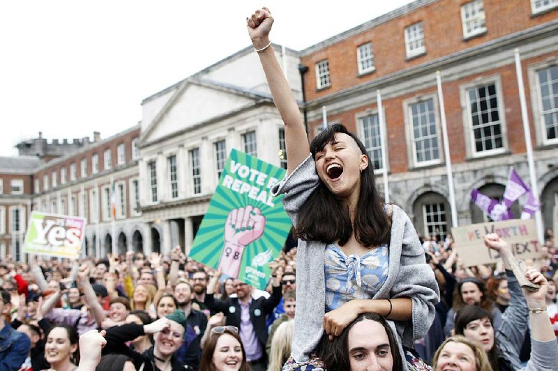 Supporters of overturning the amendment that required Irish authorities to defend the lives of a woman and a fetus as equals from the moment of conception celebrate Saturday at Dublin Castle. 