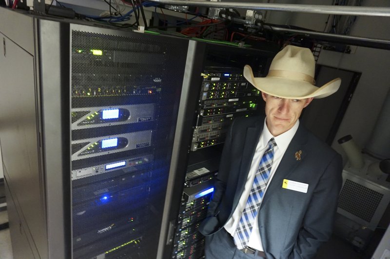 In this March 8, 2018 photo Wyoming state Rep. Tyler Lindholm poses next to computer servers in an office building in Cheyenne, Wyo. Lindholm was a lead proponent of several new laws that have made Wyoming friendly to the networked ledgering technology called blockchain. Supporters say that by welcoming blockchain, the technology underlying cryptocurrencies including bitcoin, Wyoming has become a good place for tech business. (AP Photo/Mead Gruver)