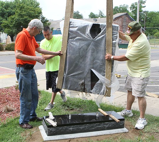 The Sentinel-Record/Richard Rasmussen PLACEMENT: From left, Dick Holden, Brandon Chrestman and Donald Newton guide the POW/MIA monument into place at the Garland County Veterans Memorial and Military Park on Tuesday.