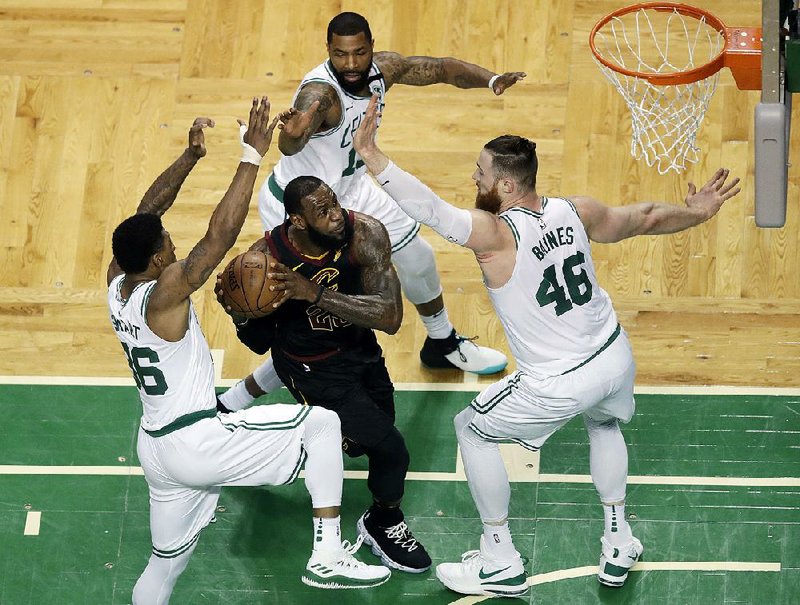 Cleveland Cavaliers forward LeBron James (center) drives through the Boston Celtics defense of guard Marcus Smart (left), forward Marcus Morris (rear) and center Aron Baynes during the first half of Game 7 of the Eastern Conference finals Sunday in Boston. Behind James’ 35 points, the Cavaliers advanced to the NBA Finals after an 87-79 victory over the Celtics. 