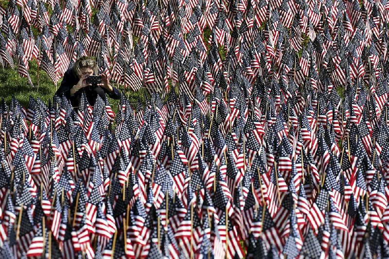 A woman photographs American flags on Boston Common in Boston. The flags are placed there for Memorial Day. 