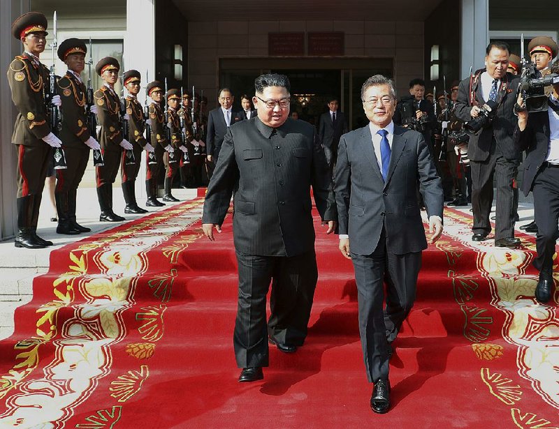North Korean leader Kim Jong Un (left) and South Korean President Moon Jae-in walk together Saturday after their meeting on the north side of Panmunjom in this photo released Sunday by South Korea’s presidential Blue House. The surprise meeting refl ected urgency to maintain diplomacy despite tensions that threatened plans for a summit between Kim and President Donald Trump. 