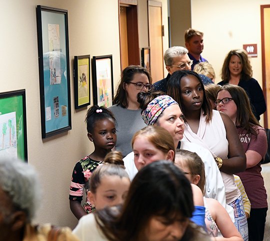 The Sentinel-Record/Grace Brown - Students from area schools line the halls of the Garland County Courthouse with their families to look at the artwork they created for the walls of the courthouse on Tuesday, May 22, 2018. The students will return in eight years once they are seniors to collect the artwork. 