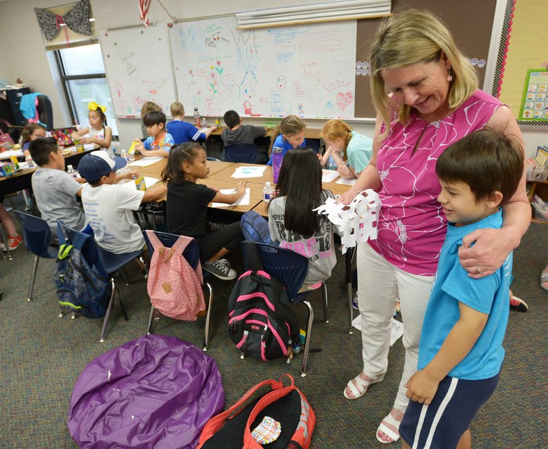 Cornelia Stark, a third-grade teacher at Walker Elementary School in Springdale, gets a hug Wednesday from student Isaiah Stewart, 9, while making crafts on the final day of the school year. Stark is retiring after a 39-year career in education and is the final person at Walker Elementary School who was there when the school opened in 1987. 