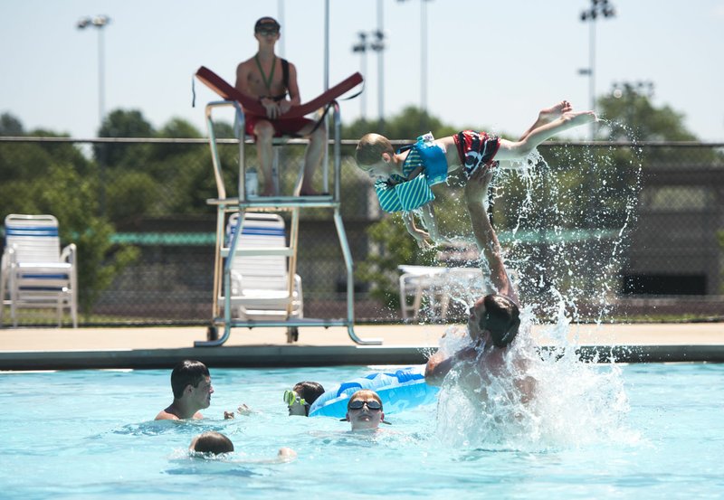 Devan Ferriel of Bentonville (right) flips Kegan Ferriel, 4, Sunday at the Melvin Ford Aquatic Center in Bentonville. The center opened for the season Saturday and will stay open until Labor Day. 