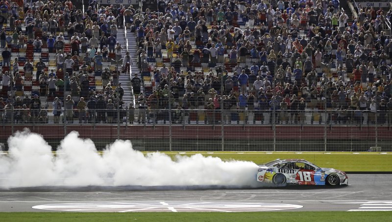 Kyle Busch celebrates after winning the NASCAR Cup Series auto race at Charlotte Motor Speedway in Charlotte, N.C., Sunday, May 27, 2018. (AP Photo/Chuck Burton)