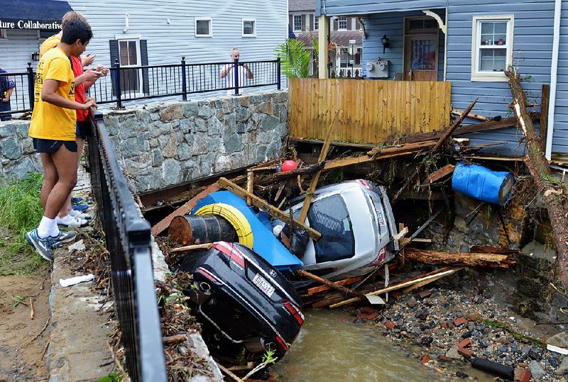 Ellicott City, Md., residents gather on a bridge Monday to look at crumpled cars left by flooding of tributaries to the Patapsco River. 
