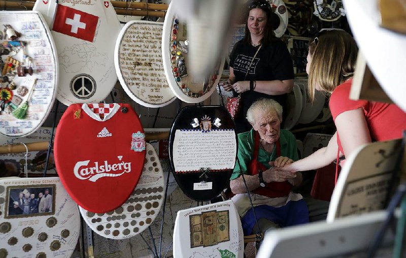 Retired plumber Barney Smith, center, greets a visitor to his Toilet Seat Art Museum in Alamo Heights, Texas. 
