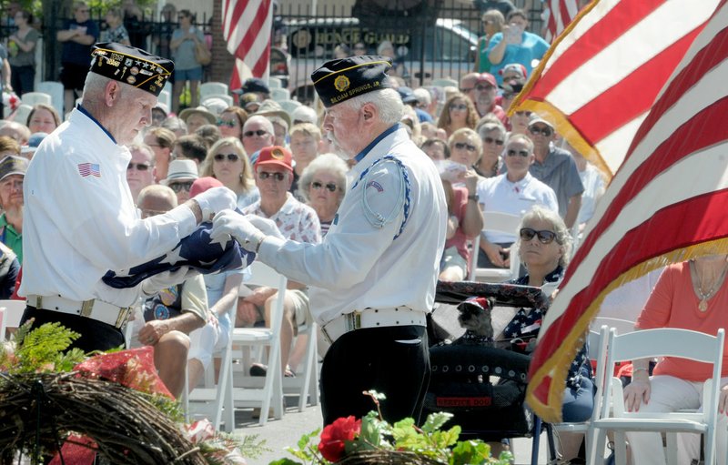 Stuart Reeves (left) and Jim Gillig, both with Siloam Springs’ American Legion post, fold the flag Monday during the Memorial Day ceremony at Fayetteville National Cemetery. The ceremony included the traditional color presentations, rifle volley, memorial wreath recognition and keynote speaker retired Col. Anita Deason. 