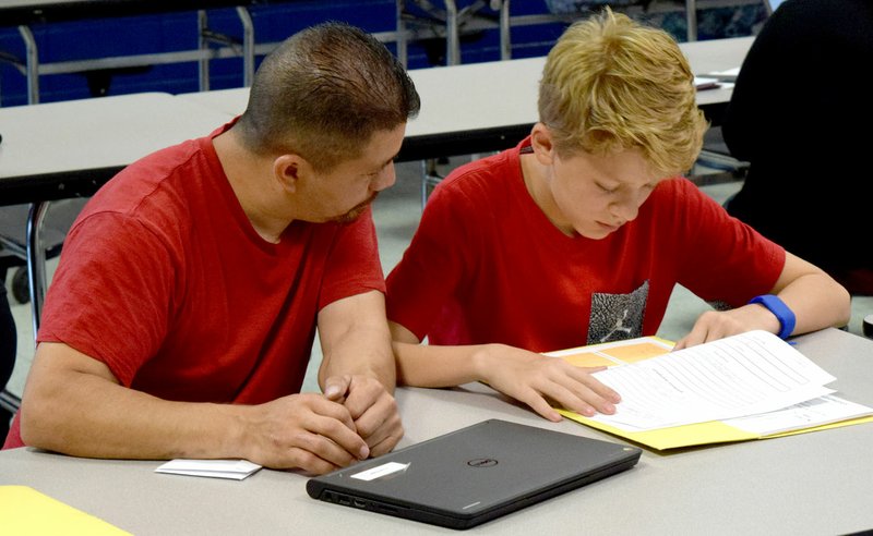 Westside Eagle Observer/MIKE ECKELS Sabino Gonzalez and his son Jayden review a homework assignment during the Decatur Middle School's quarterly Student-Led Conference in the cafeteria at Decatur High School May 15.