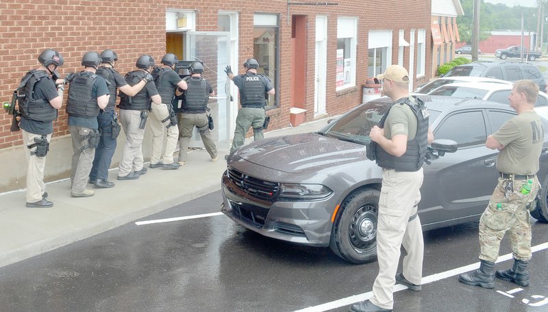 Keith Bryant/The Weekly Vista Bella Vista and Pea Ridge officers attending the departments' joint basic SWAT course enter an out-of-use Bank of Gravett building, while Bella Vista Police Department Lt. Scott Vanatta and Sgt. Eric Palmer observe.