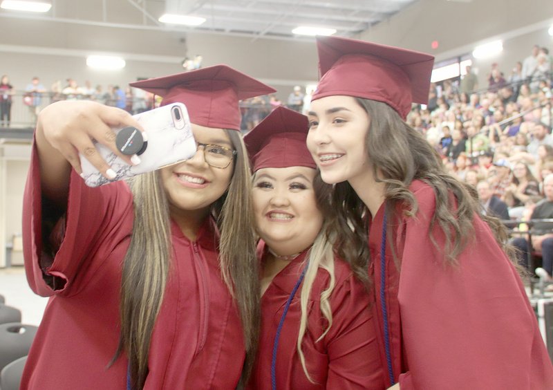 LYNN KUTTER ENTERPRISE-LEADER Lincoln 2018 graduates Jenifer Cruz, Emily Moua and Marisol Soto take selfies of themselves during Lincoln's commencement ceremony Thursday night at Wolfpack Arena. The school started this tradition several years ago. Students are given one minute toward the end of the ceremony to take out their cellphones and snap photos with their friends.