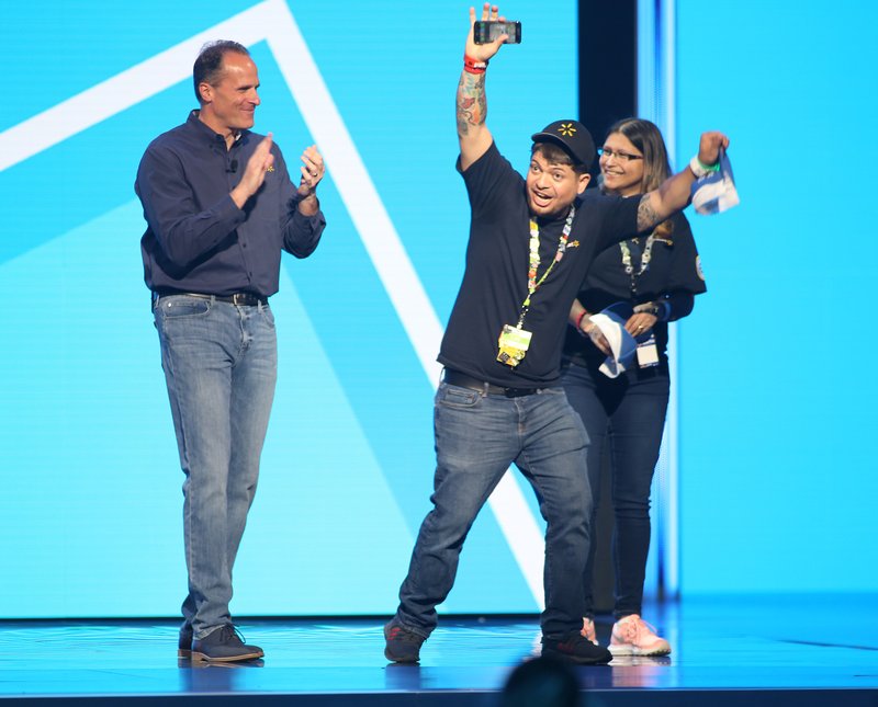 Steve Bratspies (from left), executive vice president of general merchandise for Walmart U.S., recognizes Luis Colon Mauras and Yesenia Torres, on stage during the Walmart U.S. Associates Meeting at Bud Walton Arena on the campus of the University of Arkansas in Fayetteville.