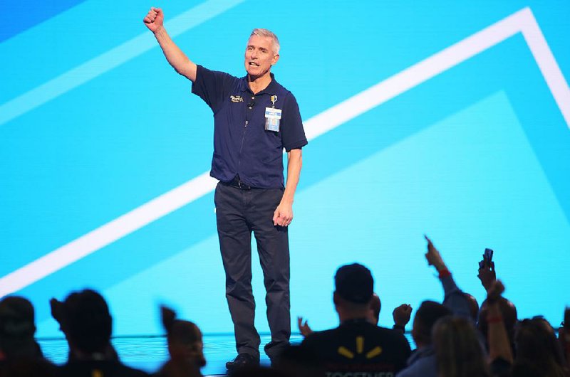 Greg Foran, president and chief executive officer of Walmart U.S., leads a cheer Wednesday during a meeting of Walmart associates at Bud Walton Arena in Fayetteville. “Investing in the personal and professional success of our associates is vital to Walmart’s future success,” he said.  