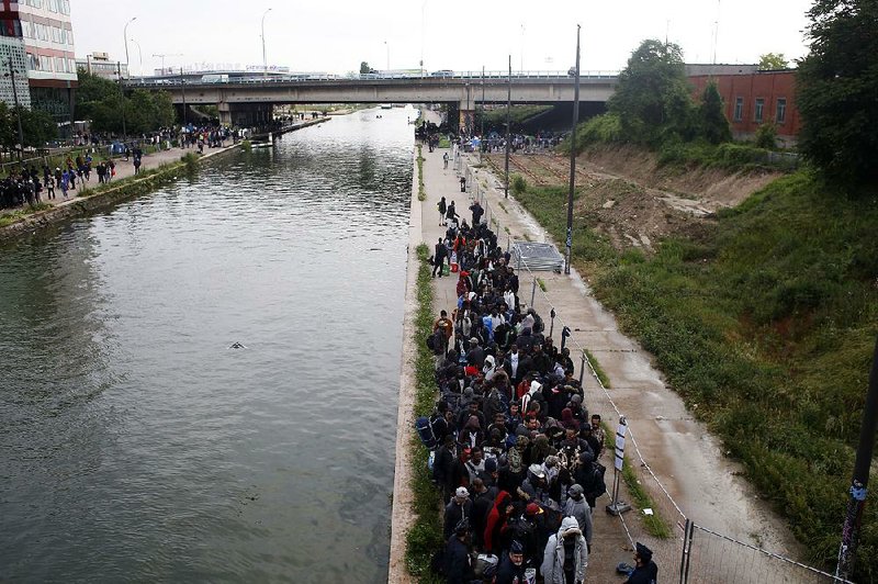 Refugees line up as they evacuate a makeshift camp Wednesday in Paris. 