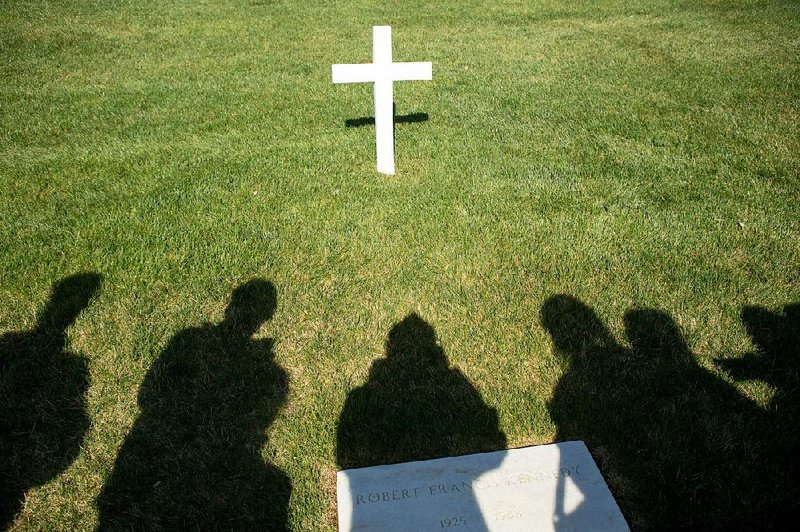 A tour group from Tupelo Christian Preparatory School in Tupelo, Miss., stands around a cross on the grave of Robert F. Kennedy at Arlington National Cemetery in Arlington, Va.  