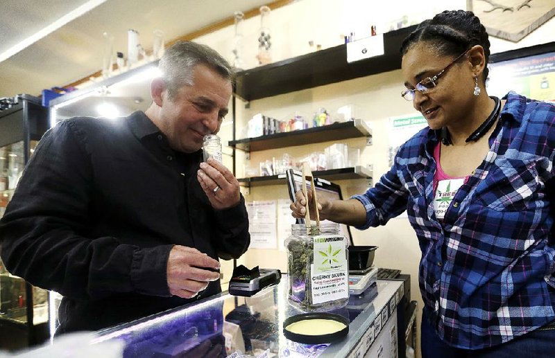 Brooke Smith, owner of the Tree PDX marijuana shop in Portland, Ore., shows Oregon Craft Cannabis Alliance executive Adam Smith a marijuana variety called Cherry Skunk. 