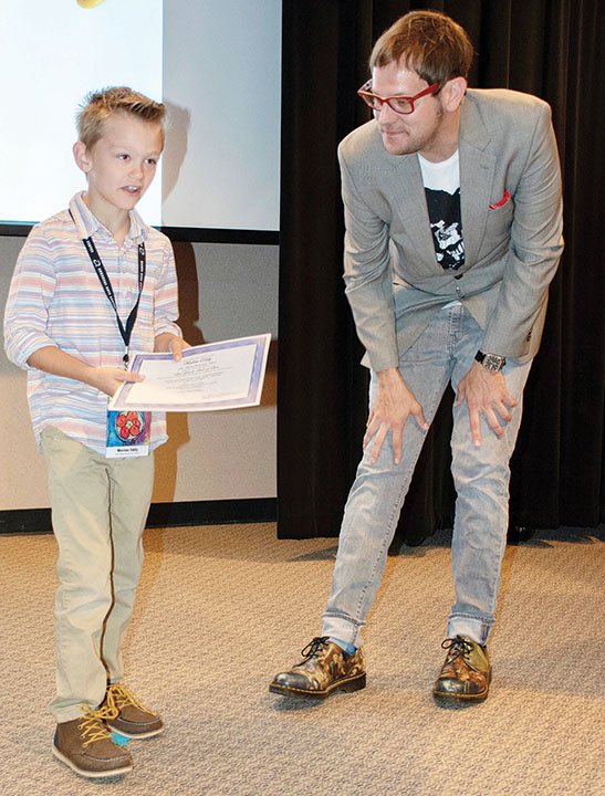 Weston Eddy, a first-grader at Pine Haven Elementary School in Bauxite, visits with Little Rock-based artist Michael Shaeffer during the awards reception for students whose works are included in the 57th Young Arkansas Artists Exhibition at the Arkansas Arts Center. As grand juror for the show, Shaeffer awarded Weston Best of Class for his tempera painting Matisse’s Apples.
