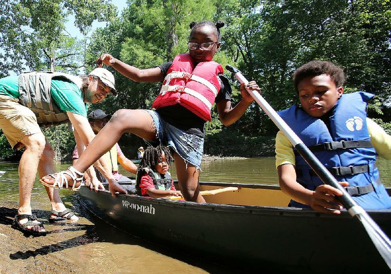 Mike Sprague keeps the canoe steady Saturday as Alexa Pinchback, 7, steps ashore and Kahmarr McClain, 12, (right) sits tight after a fl oat trip at Fourche Fest in Little Rock. 