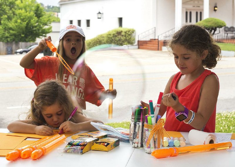 Elizabeth Burris, 8, of Fayetteville blows a bubble Saturday while taking part in the Wear Orange event with Kit Clowney, 4 and Evie Clowney, 7, at the Walker-Stone House in Fayetteville. 