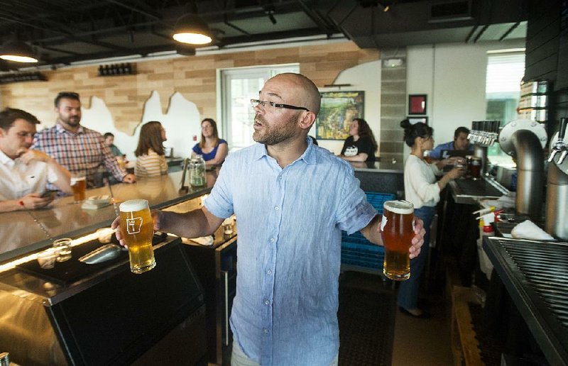 Adam Smith serves customers at Bike Rack Brewing Company’s 8th Street Market location in Bentonville. The brewer has started a record label in a branding effort to attract more customers.  