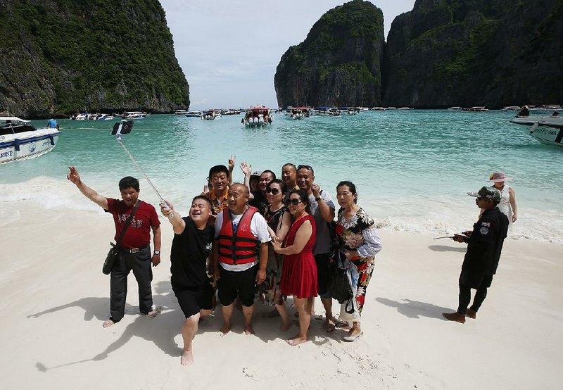 Tourists take selfies last week on the beach of Maya Bay on Thailand’s Phi Phi Leh island. The secluded bay has closed to visitors.  