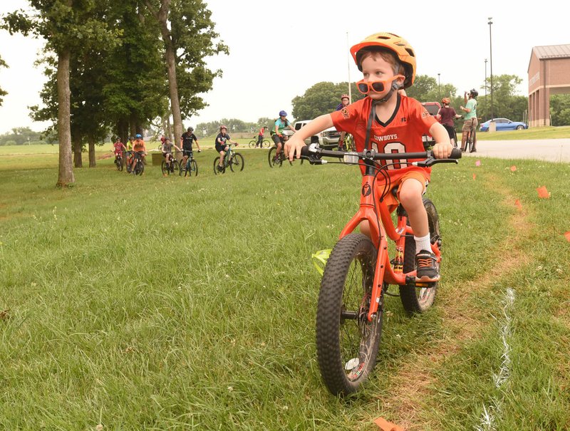 Klay Templeton, 4, risks losing his sunglasses as he bikes Saturday along the new trail near Pea Ridge High School. Dozens of bike riders, mostly team members in the National Interscholastic Cycling Association, formed the trail by riding the route over and over to create a dirt path. 