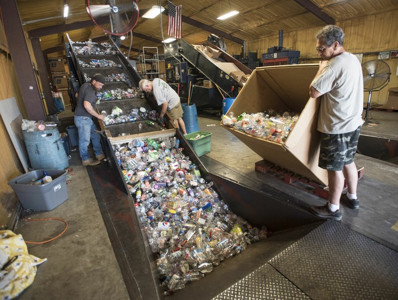 Lou Stirek (from right), Dan Gage and Atom Marcum sort plastic bottles Friday at the Bella Vista Recycling Center.  